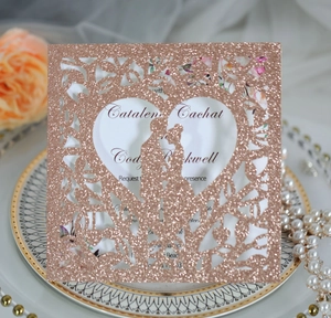 Détail du faire-part de mariage cœur découpé au laser or rose avec texture pailletée et fleurs