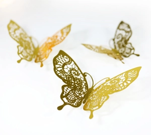 Macro shot of 3D gold hollow butterfly stickers with intricate laser-cut lace details