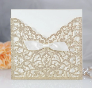 Dettaglio dell'invito di nozze glitter oro intagliato al laser con fiocco bianco