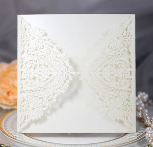 Close-up of laser-cut white wedding invitation with intricate floral lace pattern