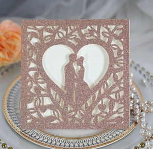 Détail d'invitation de mariage rose gold pailleté avec cœur découpé et silhouette de couple