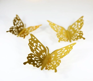 Macro detail of golden hollow butterfly wall stickers with intricate laser-cut patterns