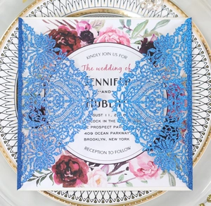 Macro detail of laser-cut wedding invitation with blue glitter finish and floral inner card
