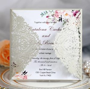 Close-up of laser-cut wedding invitation on porcelain plate with roses and pearls