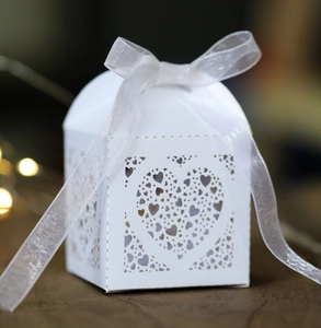Detailed close-up of white laser-cut wedding favor box with a delicate organza ribbon bow