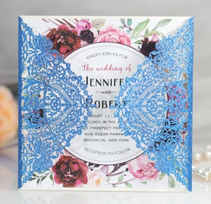 Close-up of laser-cut lace pattern on blue glitter wedding invitation with floral insert card