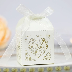 Elegant laser-cut cream wedding candy box with heart pattern and white silk ribbon bow