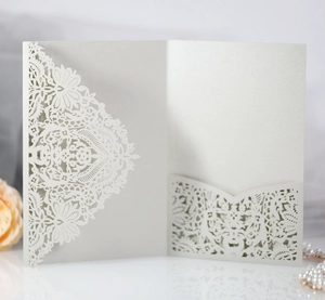 Close-up of laser-cut lace pearl white wedding invitation cover with elegant floral patterns