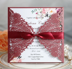 Burgundy laser-cut wedding invitation set with floral inner page and satin ribbon