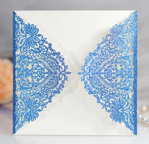 Detail of laser-cut blue glitter wedding invitation with elegant lace floral patterns