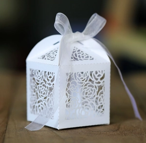 Detailansicht der weißen lasergeschnittenen Geschenkbox mit Rosenmuster und weißer Schleife