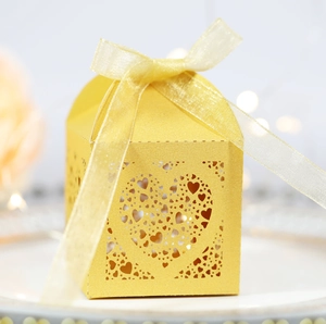 Macro shot of laser-cut heart pattern on yellow pearlescent paper wedding favor gift box