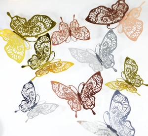Macro detail of 3D laser-cut lace butterfly wall stickers with metallic gold finish