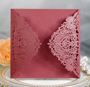 Detail of burgundy laser-cut lace wedding invitation with glitter finish and floral patterns