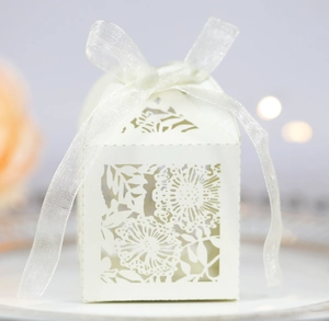 Elegant white laser-cut wedding favor box with floral patterns and a sheer ribbon bow