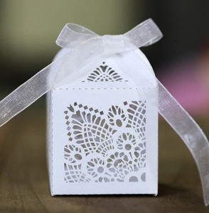 Elegant white laser-cut wedding candy box with intricate lace pattern and organza ribbon