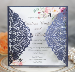 Detail of laser-cut navy blue wedding invitation with elegant white floral inner card