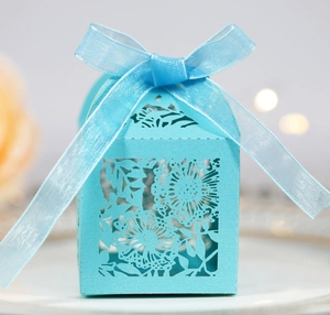 Detail of light blue laser-cut floral wedding favor box with an elegant ribbon bow