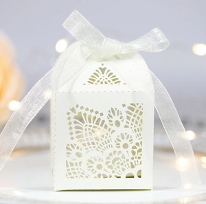White laser-cut hollow paper wedding favor box with elegant organza ribbon bow