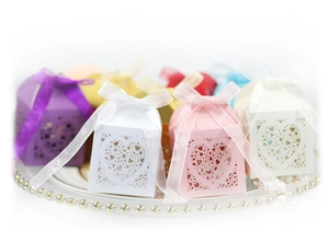 Laser-cut heart favor boxes in multiple colors with silk ribbons on elegant plate