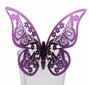 Papillon décoratif violet découpé au laser posé sur le rebord d'un verre en détail