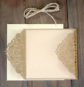 Laser-cut kraft paper wedding invitation with intricate lace floral patterns and hemp rope