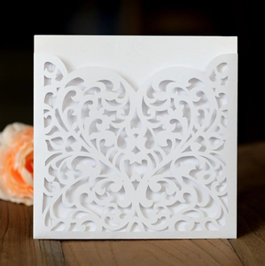 Detail of laser-cut heart wedding invitation with intricate vine patterns on wood