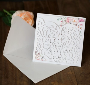 Detail of laser-cut wedding invitation with elegant floral insert and white envelope