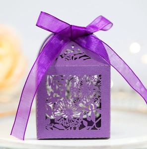 Detail of laser-cut sunflower pattern on purple wedding candy box with silk ribbon bow