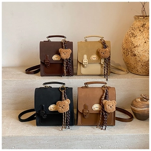 Detail showing four colors of vintage mini backpacks with cute charms on stone steps
