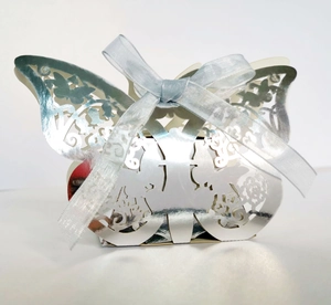 Détail d'une boîte à dragées papillon argentée découpée au laser avec ruban bleu élégant