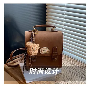 Close-up of vintage brown backpack with cute bear embroidery and plush charm pendant