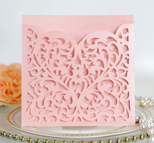 Close-up of pink laser-cut heart invitation card with pearl finish on a decorative plate