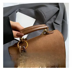 Detail of brown vintage handbag with matte suede texture and cute teddy bear charm