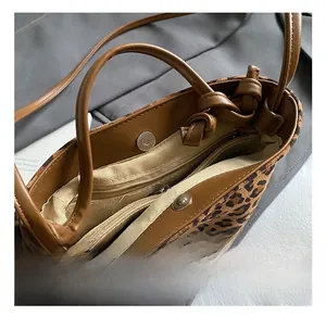 Detail shot of leopard print bucket bag interior showing zip compartment and magnetic closure