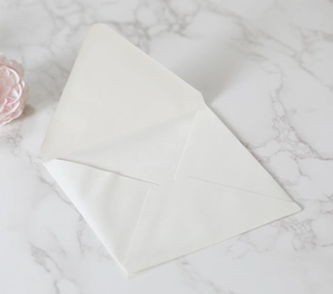 Detail of premium ivory pearlescent paper envelope on minimalist marble background