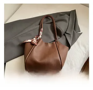 Dettaglio della borsa tote marrone scuro con piedini in metallo e foulard
