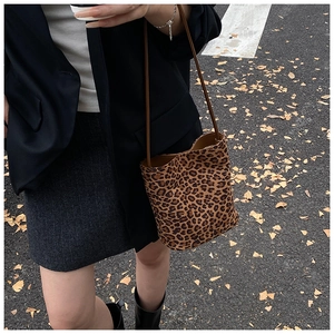 Détail d'un sac seau à motif léopard avec une fine bandoulière marron en extérieur