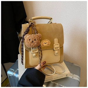 Detail of vintage brown leather backpack with cartoon puppy patch and plush bear charm