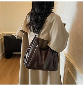 Macro shot of dark brown retro leather tote bag with silver side zipper and tassel detail