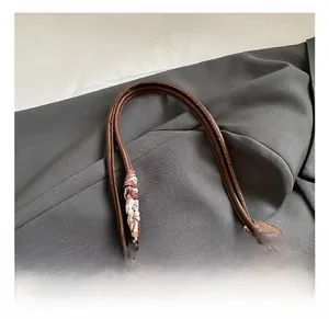 Dettaglio borsa tote in pelle marrone scuro con trama a litchi e foulard in seta decorativo