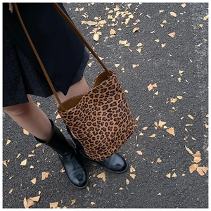 Détail du sac seau imprimé léopard sur des feuilles d'automne avec bandoulière marron
