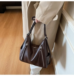 Detail of deep brown retro PU leather tote bag with silver zippers on a model
