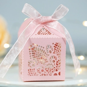 Elegant ivory laser-cut wedding candy box with pink ribbon and floral pattern