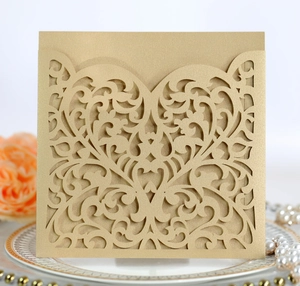 Detail of laser-cut gold wedding invitation with intricate floral lace and heart pattern