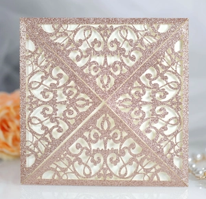 Detail of laser-cut rose gold glitter wedding invitation with elegant lace pattern