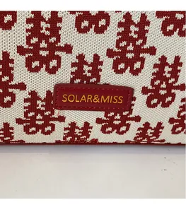 Close-up of red and white knitted tote bag with Xi character jacquard and leather logo