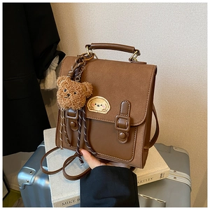 Detail of a brown vintage backpack with a cute dog patch and plush bear accessory