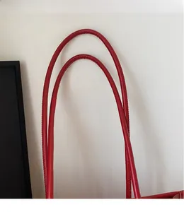Detail of red leather tote bag showing smooth shoulder straps and fine stitching texture