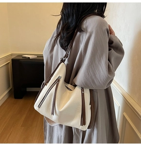 Detail of off-white leather tote bag with silver zippers and dark brown shoulder straps